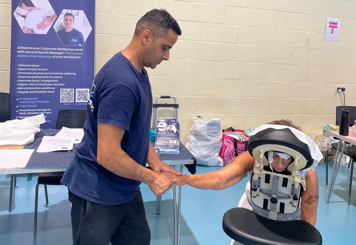 Pramod treating a team member in the massage chair at a workplace wellbeing day